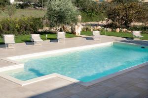 a swimming pool with white chairs and a patio at Resort Pietra Bianca in Noci