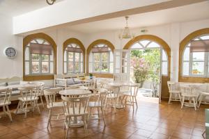 a dining room with tables and chairs and windows at Joanna Apart - Hotel in Grikos