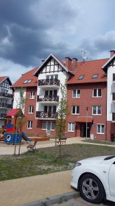 a white car parked in front of a building with a playground at Apartament dla Ciebie in Sztutowo