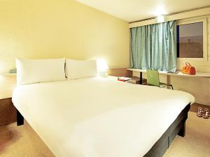 a large white bed in a room with a window at Hotel ibis Guimaraes in Guimarães