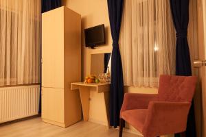 イスタンブールにあるマイ ホーム スルタンアフメット ホテルの椅子とテレビが備わる客室です。