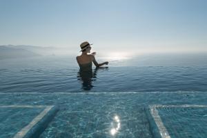 a man standing in the water with a boogie board at Grand Miramar All Luxury Suites & Residences in Puerto Vallarta