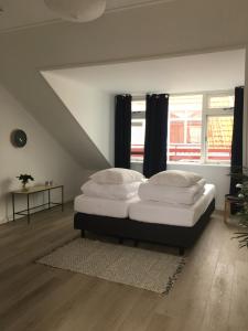 een slaapkamer met een bed met witte kussens erop bij Kamers van Goud in Katwijk aan Zee