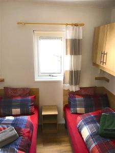 ブーフローエにあるAllgäu-Chaletのベッド2台と窓が備わる小さな客室です。