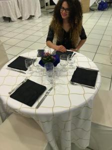 una donna seduta a un tavolo con bicchieri da vino di Hotel Seven Residence a Palinuro