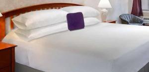 uma grande cama branca com almofadas brancas em Knights Inn Greenville em Greenville