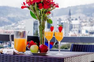 a table with two glasses and a vase of flowers and fruit at Báltico in Quito