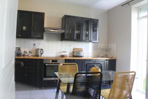 a kitchen with black cabinets and a table and chairs at Le Logis GOUT - L'Oustal in Carcassonne