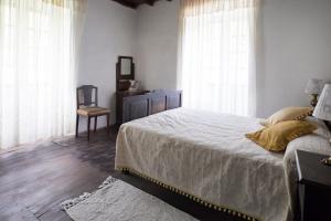 a bedroom with a bed with white sheets and windows at A Fonte das Bodas in Samos