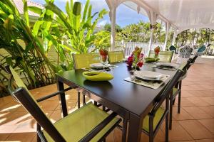 a wooden table with green chairs and a tableasteryasteryasteryasteryasteryasteryastery at Villa Cattleya 4 chambres, villa avec piscine privée et grande terrasse couverte in Le Vauclin