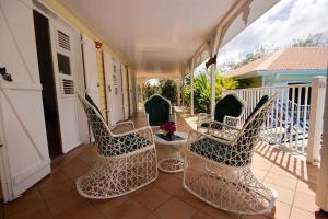 a porch with chairs and a table on a balcony at Villa Cattleya 4 chambres, villa avec piscine privée et grande terrasse couverte in Le Vauclin