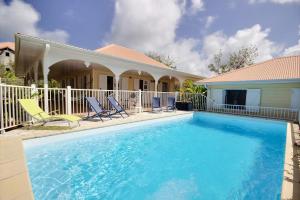 a swimming pool with chairs and a house at Villa Cattleya 4 chambres, villa avec piscine privée et grande terrasse couverte in Le Vauclin
