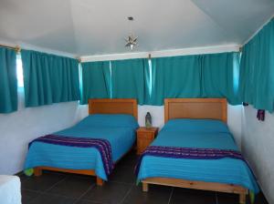 Casa Culhuac في مدينة ميكسيكو: سريرين في غرفة مع ستائر زرقاء