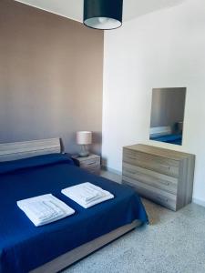 マティーノにあるAppartamento Via del Mareのベッドルーム1室(青いシーツと鏡付きのベッド1台付)