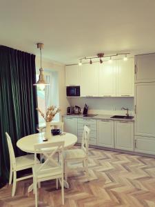 a kitchen with a white table and chairs and a table and a kitchen at Cosy center Apartment in Klaipėda
