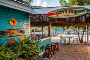 a bar with a surfboard on the side of a beach at The Verandah Antigua - All Inclusive - Adults Only in Willikies