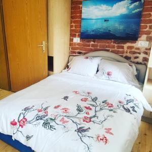 a bed with a white blanket with flowers on it at Sirma's Studio - Artsy Quiet 1-Bdrm in the Prime Center of Skopje in Skopje