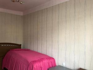 a bedroom with a pink bed and a table at Roomie1 in Yerevan