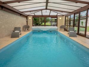 a large swimming pool with chairs and a table at Holiday Home for 10 Guests With Pool Spa and Sauna in Vaudelnay