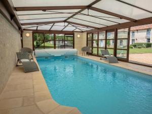 a swimming pool with chairs in a building at Holiday Home for 10 Guests With Pool Spa and Sauna in Vaudelnay
