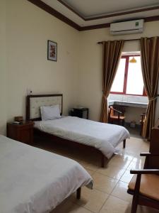 una camera d'albergo con due letti e una finestra di Le Thanh Hotel a Hai Phong