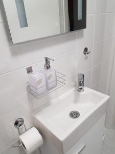 a white bathroom with a sink and a mirror at Apartment Kristina in Otočac