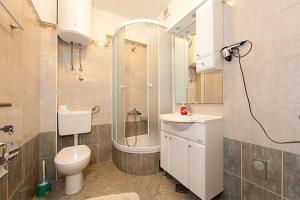 een badkamer met een toilet, een douche en een wastafel bij Apartmani Šarić in Tučepi