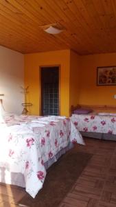 a bedroom with two beds with white sheets and flowers at Pousada Pinhalense in Santo Antônio do Pinhal