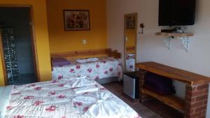 a bedroom with two beds and a flat screen tv at Pousada Pinhalense in Santo Antônio do Pinhal