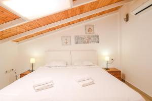 カシュにあるKasinn Apart Hotelの白いベッドと木製の天井が備わるベッドルーム1室が備わります。