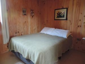 a bedroom with a bed in a wooden wall at Casa Aconchegante em Urubici in Urubici