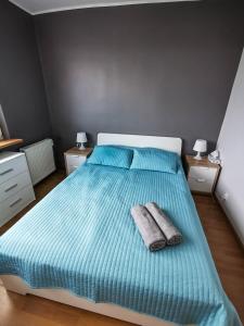 1 dormitorio con 1 cama azul y 2 toallas en Sky Apartments - Łagiewniki, en Cracovia