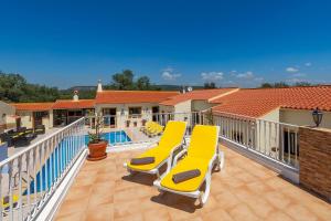 a balcony with yellow chairs and a swimming pool at Casa dos Ninos in São Bartolomeu de Messines