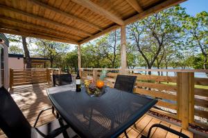 einen schwarzen Tisch und Stühle auf einer Holzterrasse in der Unterkunft Eurocamp Mobile Homes at Campsite Puntica in Funtana