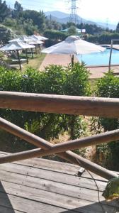 une terrasse en bois avec un parasol et une piscine dans l'établissement Refugios Olmue Santa Teresa, à El Maqui