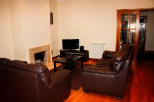 a living room with two leather chairs and a fireplace at Arco Da Porta Nova in Braga