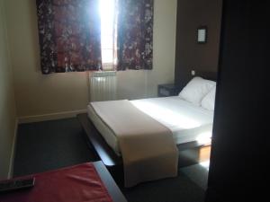 a bedroom with a white bed and a window at Hôtel Cuulong in Labarthe-Inard
