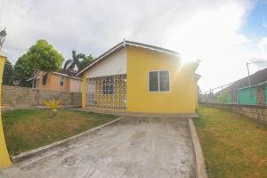 a yellow house with a fence in a yard at Chin Cozy@ Rhyne Park in Montego Bay