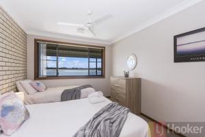 two beds in a room with a window and a tv at Peninsula Court 6 - LJHooker Yamba in Yamba