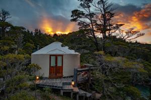 a yurt in the woods with a sunset in the background at Patagonia Camp in Torres del Paine