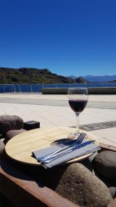 a glass of wine sitting on a wooden table at Costanera Apart in Chile Chico