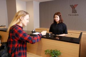 大阪市にあるワイズキャビン大阪難波の女が現金のレジに立っている