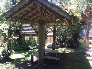 uma pérgola de madeira com um banco num quintal em Residencia Utopia em São Francisco de Paula