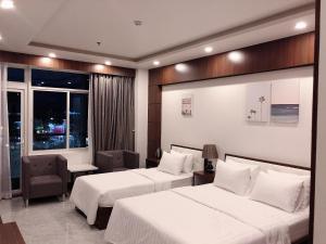 Long KhanhにあるQuốc Thanh Hotelのベッド2台と窓が備わるホテルルームです。
