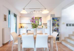 a kitchen and dining room with a wooden table and white chairs at Nefeli Villas in Hersonissos