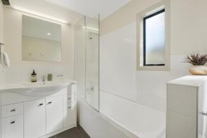 a white bathroom with a sink and a shower at Suburb Retreat in Queenstown