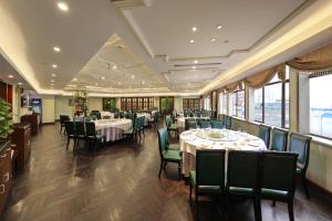a dining room with tables and chairs and windows at Seventh Heaven Hotel in Shanghai