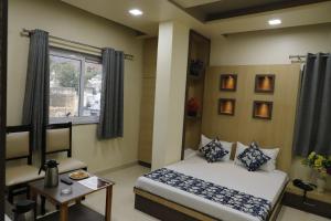a bedroom with a bed and a table and a window at Hotel Royal Suites in Ajmer