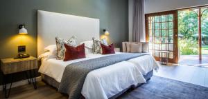 a bedroom with a large bed and a large window at Hlangana Lodge in Oudtshoorn