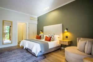 a bedroom with a large bed and a chair at Hlangana Lodge in Oudtshoorn